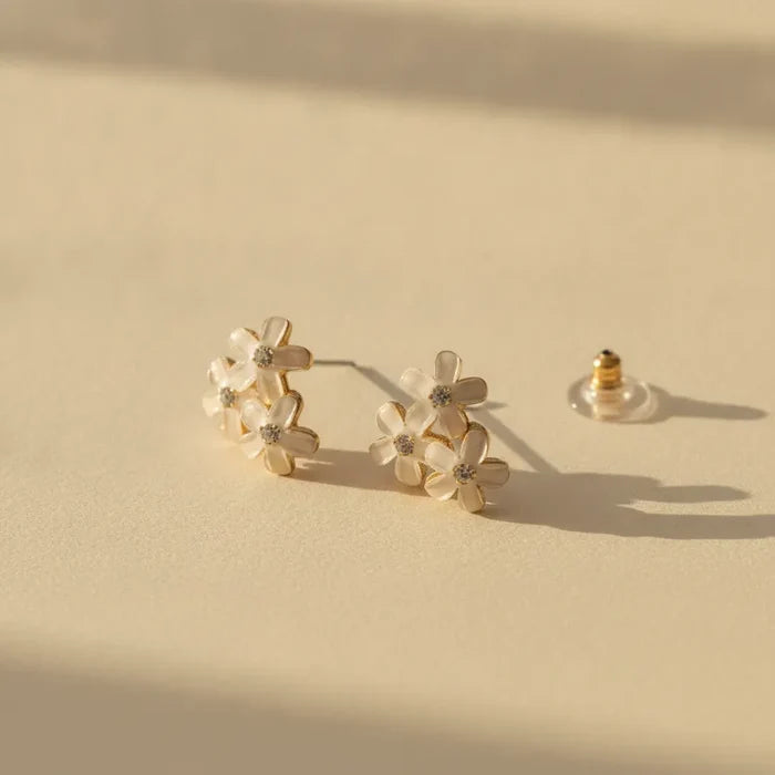 Dainty blue floral enamel flower stud earrings with gold-toned settings and clear gemstone centers