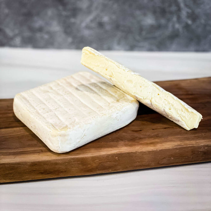 ROBIOLA BOSINA Alta Langa soft-ripened cheese made from sheep and cow milk on wooden board.