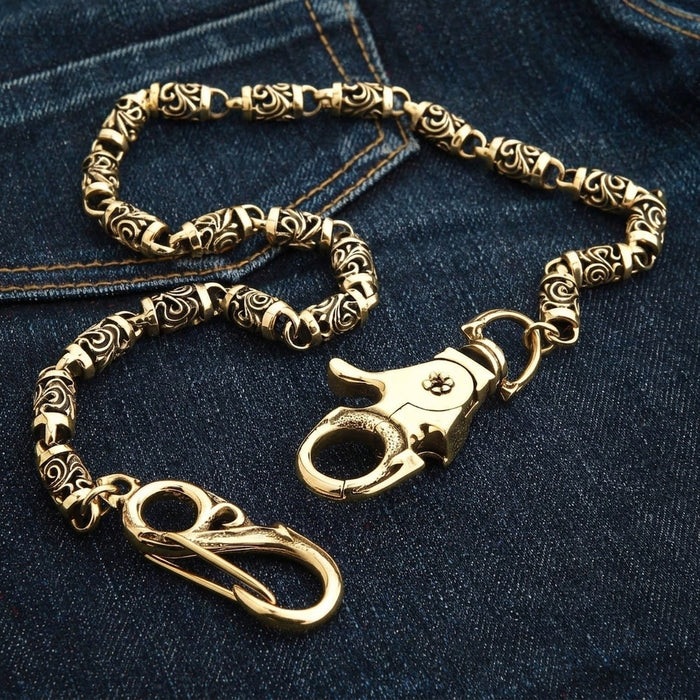 Reverse face of the brass lobster claw clasp with its small flower rivet and oval bail, resting on dark denim.