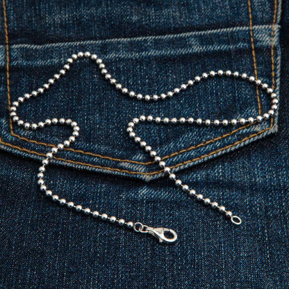 The polished 3mm silver ball chain resting on a jeans pocket.