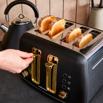 Black toaster with gold accents and four slices of toast, next to a black kettle.
