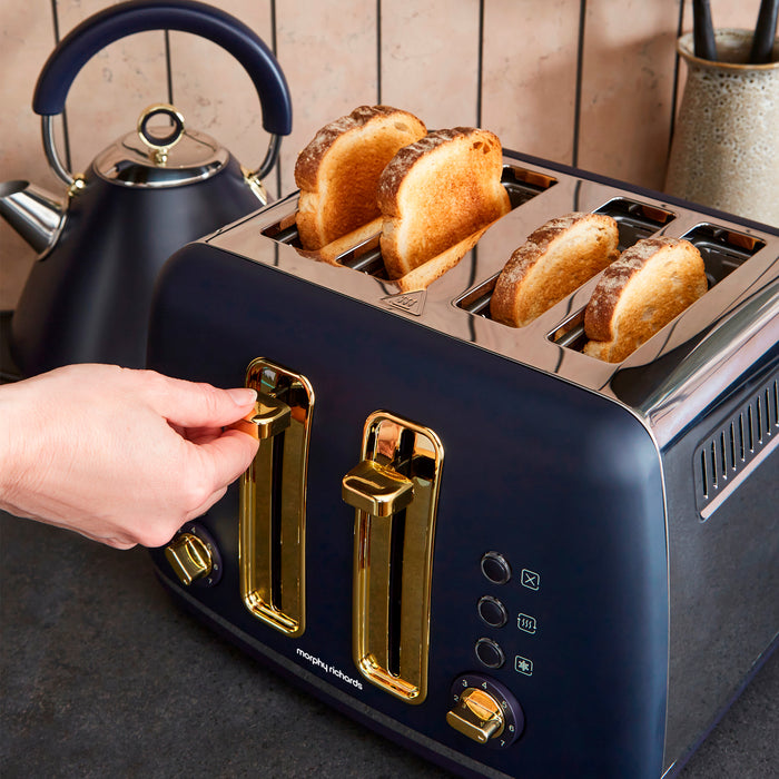 Navy blue toaster with gold accents and four slices of toast, next to a black kettle.