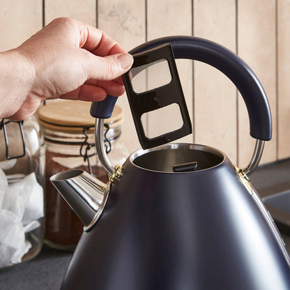 Person opening a black electric kettle with a wooden background