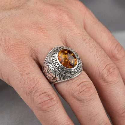 A man's hand wearing the large silver and amber tarot signet ring.