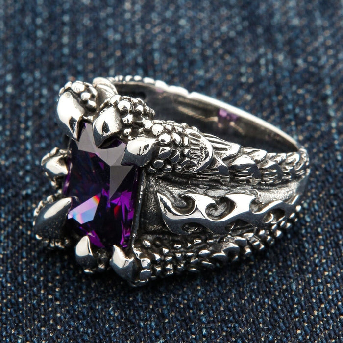 An angled view of the heavy silver amethyst claw ring on a dark denim background.