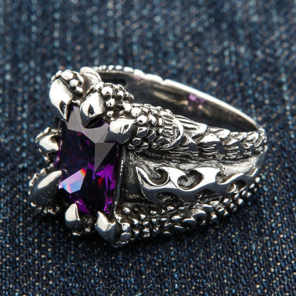 An angled view of the heavy silver amethyst claw ring on a dark denim background.