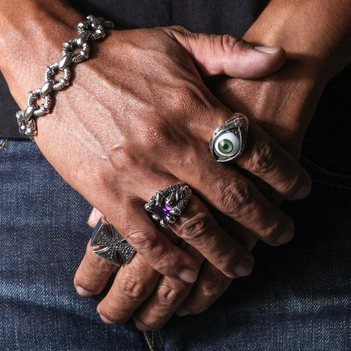 A man's hands wearing a collection of rings, with the large purple stone eagle claw ring featured.