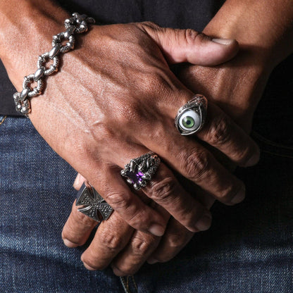 A man's hands wearing a collection of rings, with the large purple stone eagle claw ring featured.