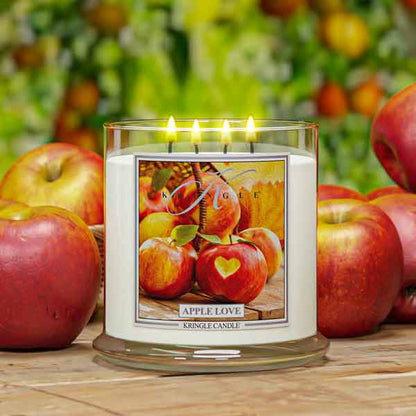Kringle Candle with 4-wick candle 'Apple Love' design surrounded by apples on a wooden surface