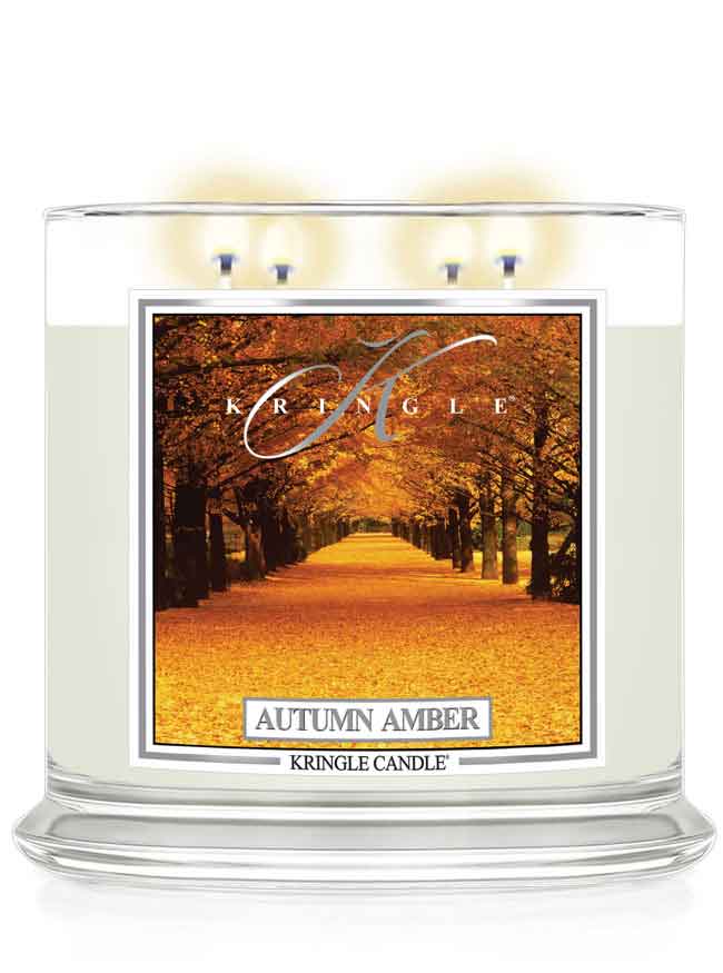 Kringle Candle Autumn Amber lit 4-wick candle with an autumn scenic label of trees and fall leaves