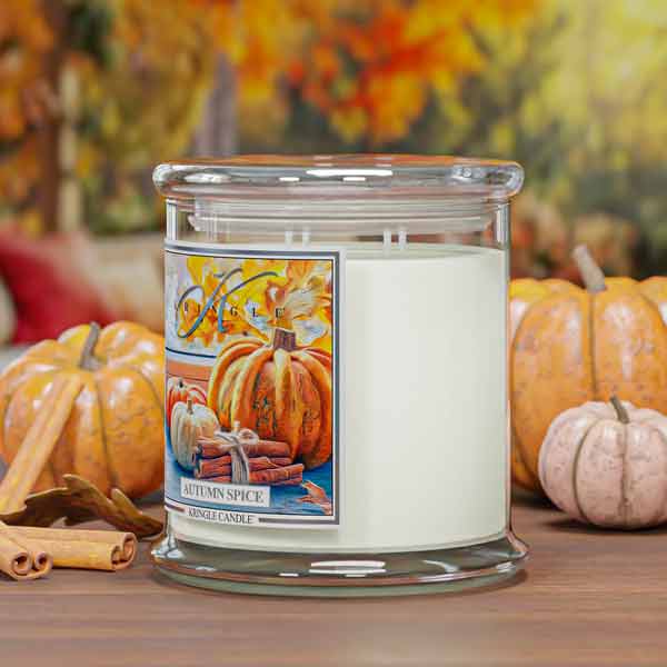 Autumn spice scented 4-wick candle with pumpkins and cinnamon sticks on a wooden surface