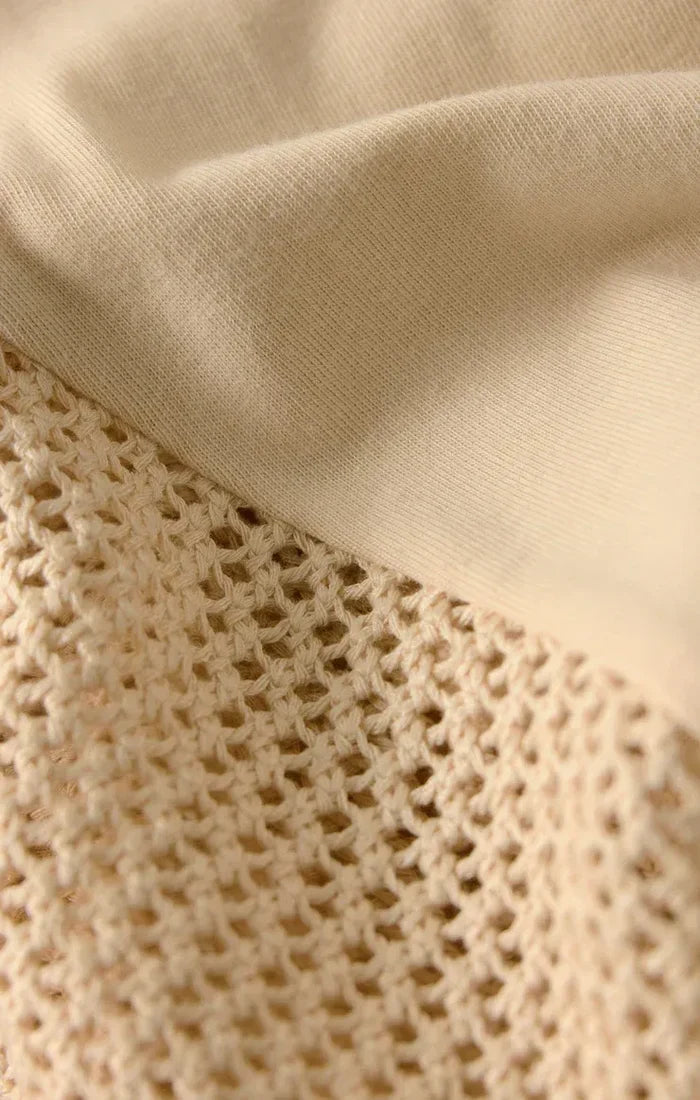 Cream-colored knit fabric with delicate openwork pattern on banyan crochet relaxed pants made of breathable crochet material