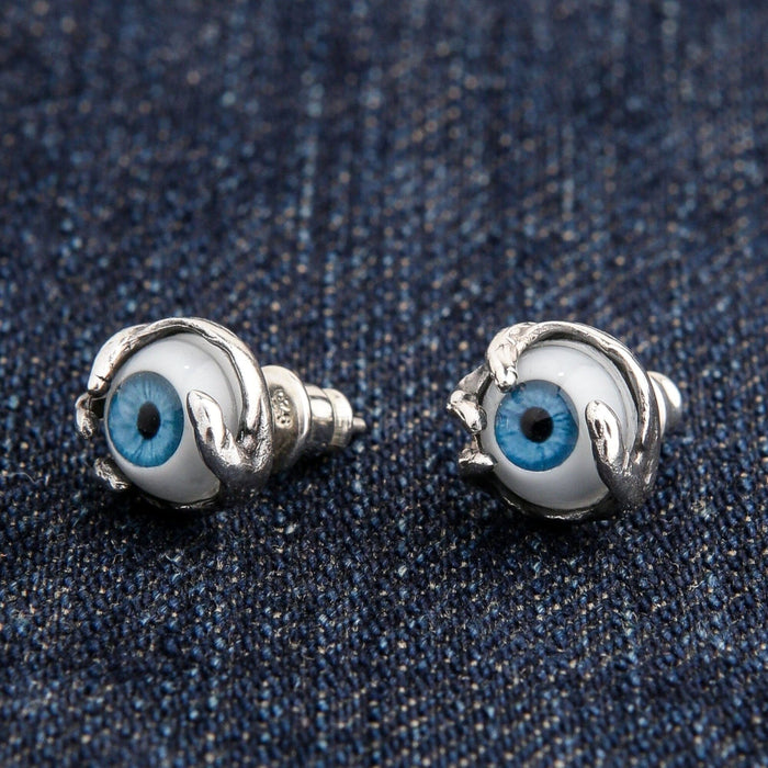 An angled view of the 10mm gothic eyeball claw stud earrings on a denim background.
