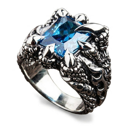 Top-down angle looking onto the blue topaz held by four eagle talons above the flame-carved band