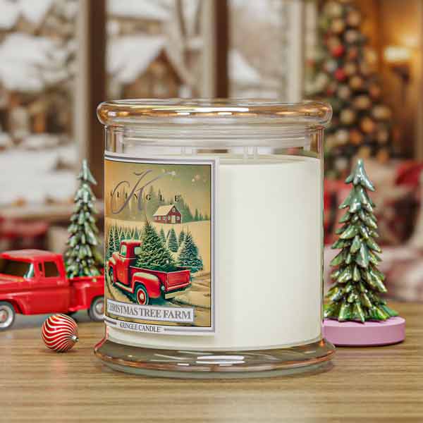 Candle with a Christmas tree farm label on a table with festive decorations.