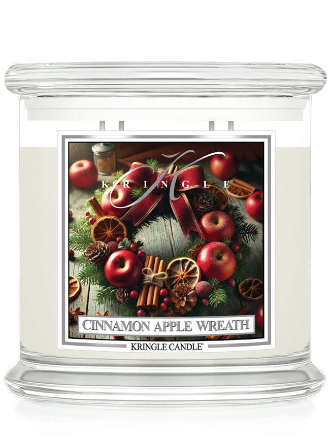 4-wick candle labeled "Cinnamon Apple Wreath" by Kringle, featuring apples, cinnamon, and holiday decorations.