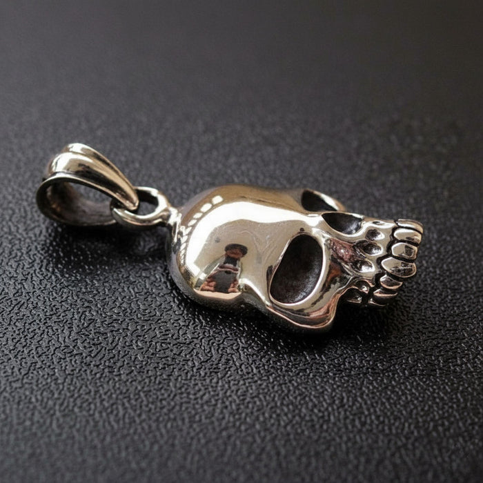 A side profile of the polished silver skull pendant, showing its three-dimensional depth and menacing grin.