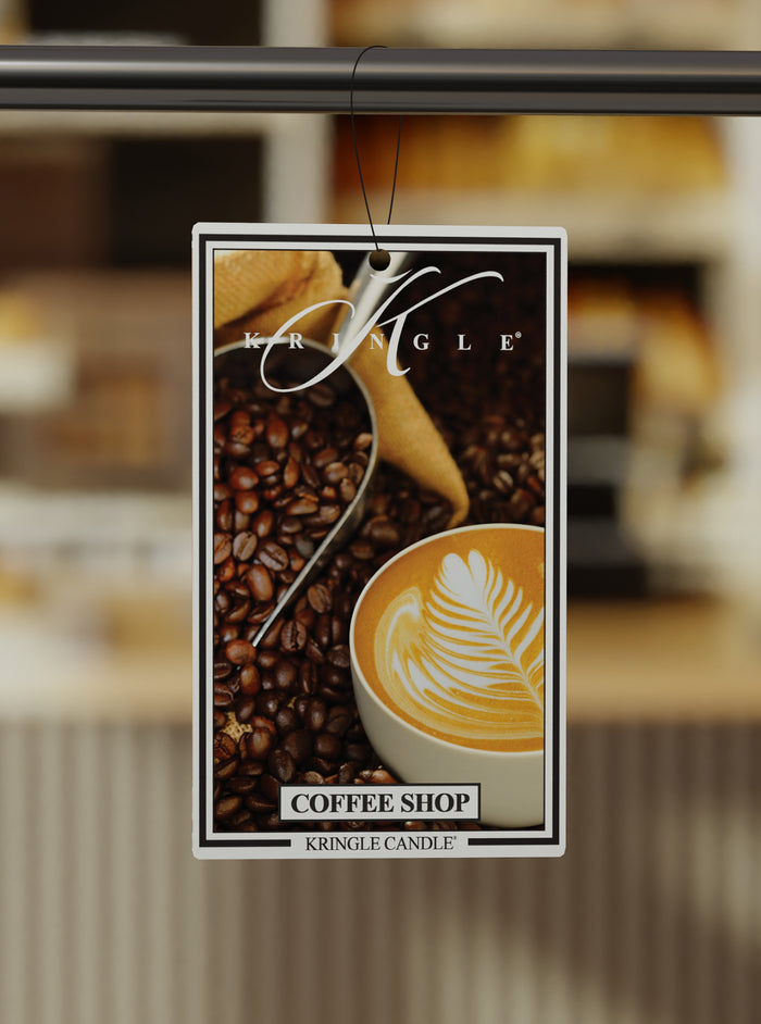 Kringle Candle Coffee Shop air freshener with coffee beans and a cup of coffee on a blurred background