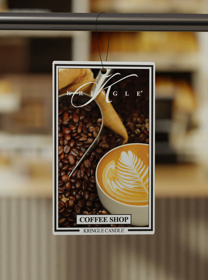Kringle Candle Coffee Shop air freshener with coffee beans and a cup of coffee on a blurred background