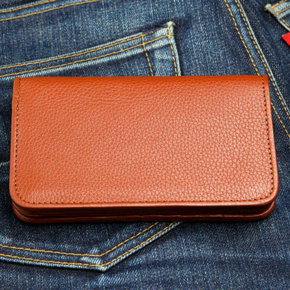 Pebble-grain cognac leather resting in a denim pocket, edge stitching running the full perimeter.