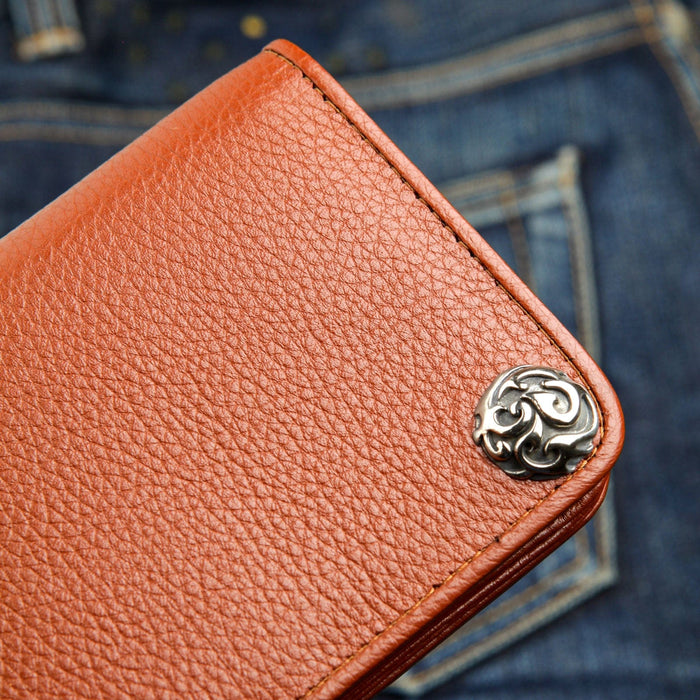 A close-up detail shot of the intricate sterling silver flame-style concho on a rich brown leather wallet.