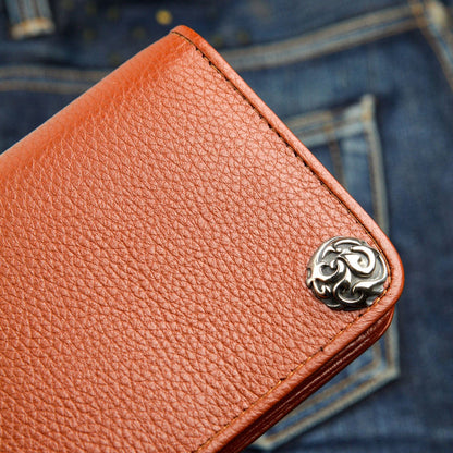 A close-up detail shot of the intricate sterling silver flame-style concho on a rich brown leather wallet.