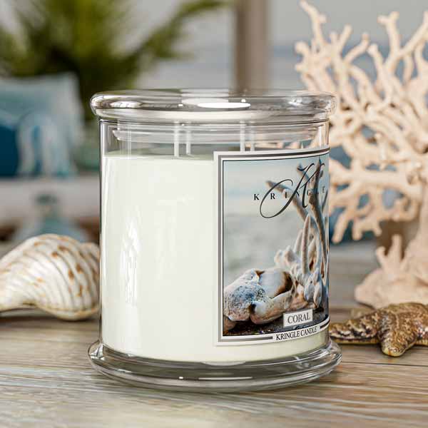 Kringle Candle coral scented candle with decorative shells and coral in the background