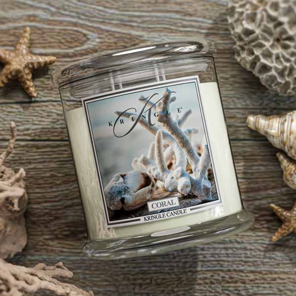 Kringle Candle coral-themed candle on a wooden surface with decorative shells and starfish.