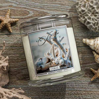 Kringle Candle coral-themed candle on a wooden surface with decorative shells and starfish.