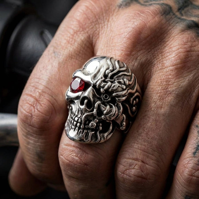 Close-up of cyborg skull ring with ruby eye worn on finger showing half-human half-machine design