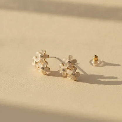 Dainty blue floral enamel flower stud earrings with gold-toned settings and clear gemstone centers