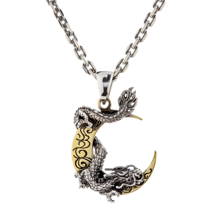A front view of the sterling silver dragon and brass crescent moon pendant on a silver chain.