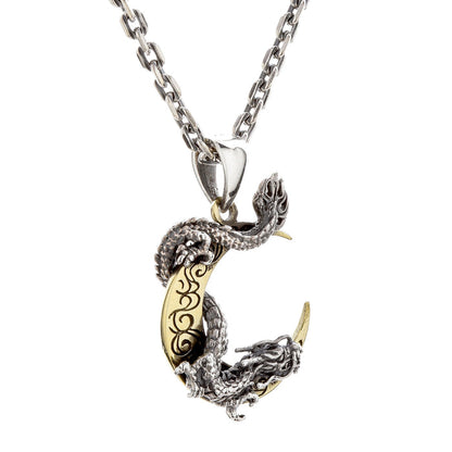 An angled view of the two-tone dragon and moon pendant, showing the detailed silver dragon scales.