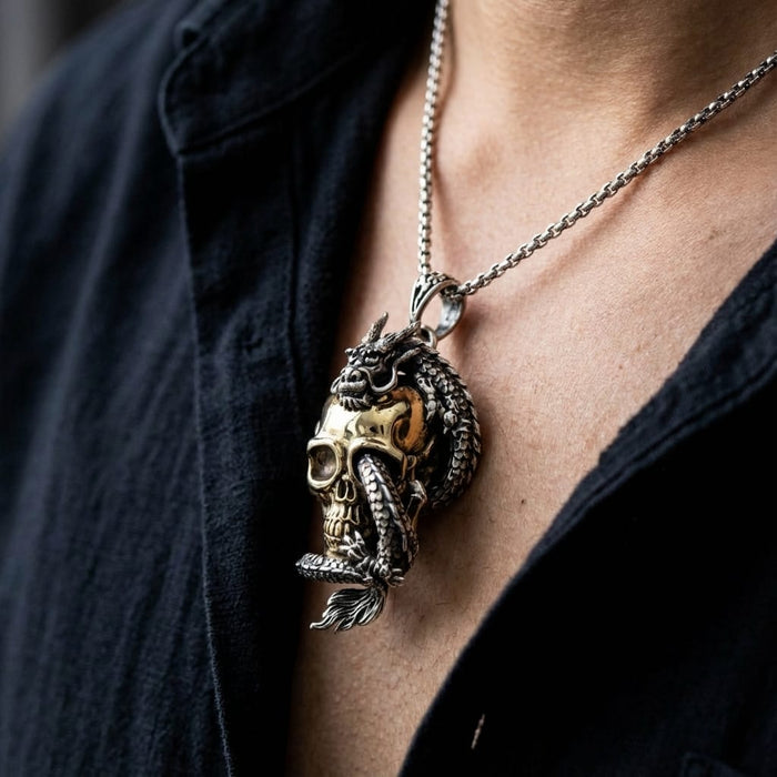 Close-up lifestyle photo of a person wearing a sterling silver chain necklace with a detailed dragon wrapped around a gold-tone skull pendant against a dark shirt.