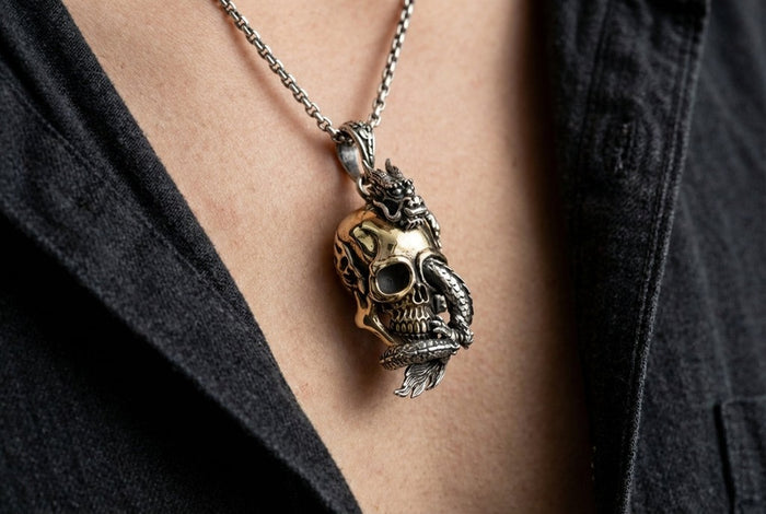 Lifestyle shot of dragon and brass skull pendant worn on a chain necklace