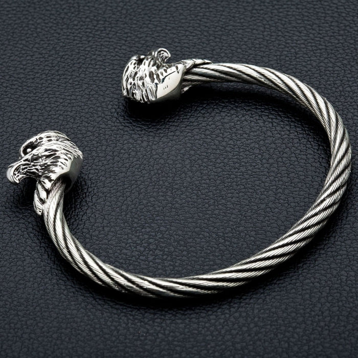 The two-tone silver and steel eagle bracelet resting on a leather background.