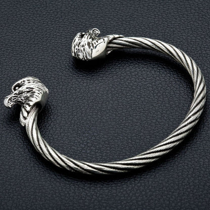 The two-tone silver and steel eagle bracelet resting on a leather background.