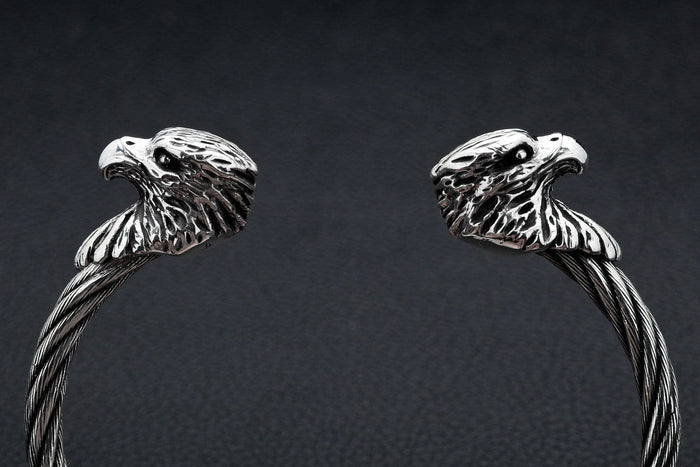 A close-up macro shot of a polished sterling silver eagle head on the textured, twisted steel cuff.