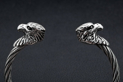 A close-up macro shot of a polished sterling silver eagle head on the textured, twisted steel cuff.
