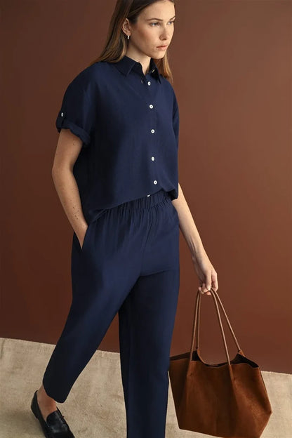 Navy blue short-sleeved button-up shirt with rolled cuffs paired with elastic waist crop pants for a stylish look