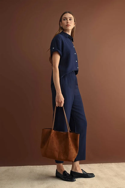 Brown suede tote bag with long handles paired with elastic waist crop pants for casual and stylish wear