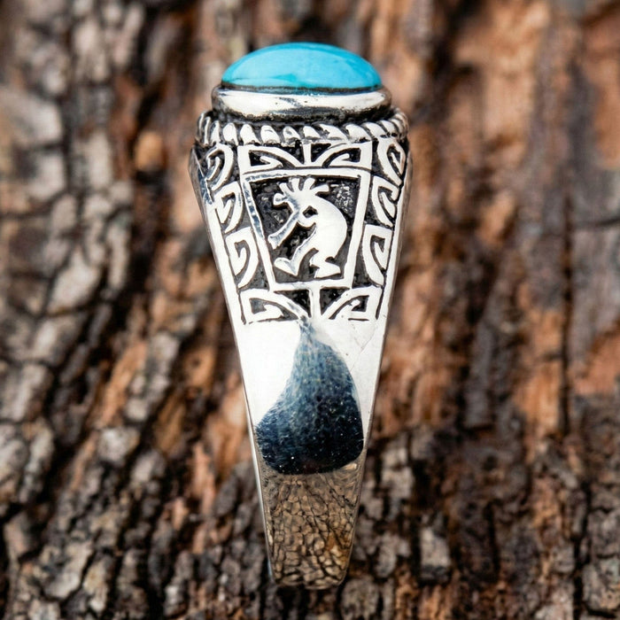 Close-up detail of the Kokopelli flute player figure engraved on the side of the silver ring.