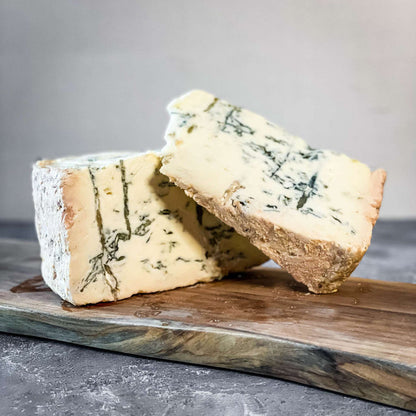 Gorgonzola Dolce DOP Ciresa cheese wedge on a wooden board with creamy blue veins.