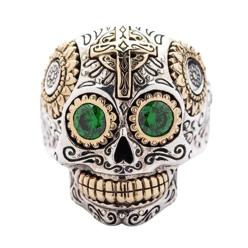 A sterling silver sugar skull ring with vibrant green CZ eyes and golden brass accents.