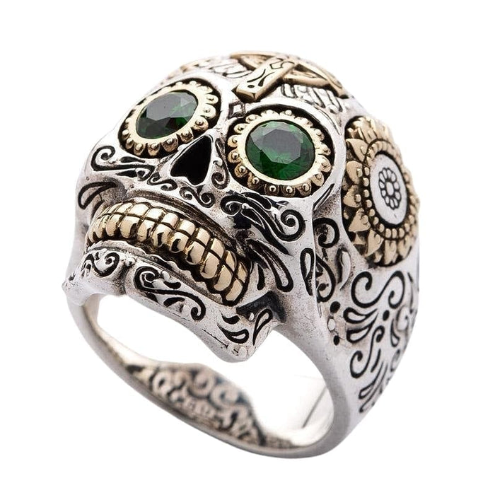 A handcrafted Calavera-style skull ring featuring brilliant emerald-green eyes.
