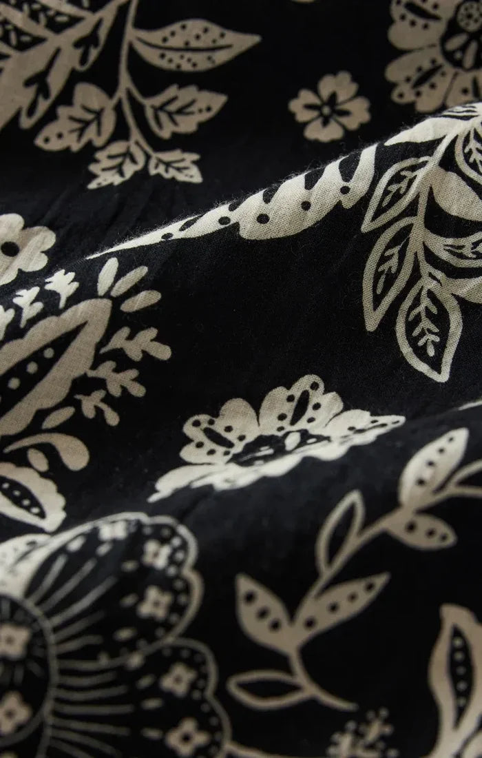 Black fabric with intricate cream floral and leaf patterns on halter viento luz floral midi dress