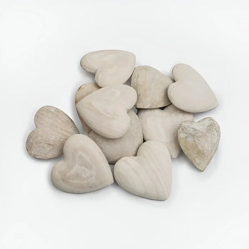 Carved wooden heart surrounded by a pile of white pebbles on a white background