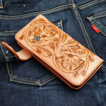 The hand-tooled cowboy wallet sitting on the back pocket of a pair of dark jeans.