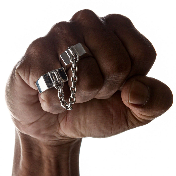 A man's fist wearing the heavy sterling silver handcuff chained double ring, showcasing its punk style.