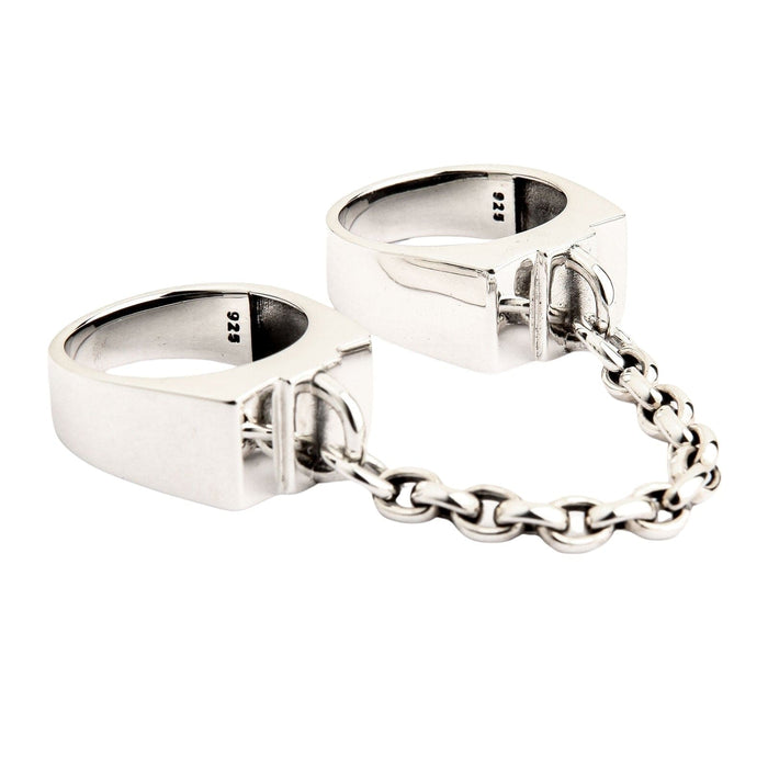 An angled view of the gothic double ring with a connecting chain, showing its industrial design.